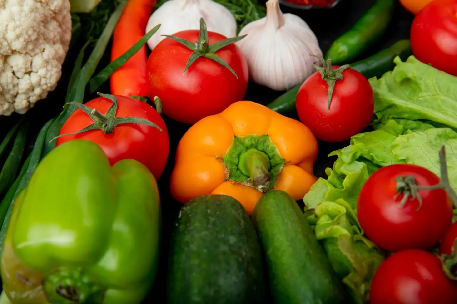 Close-up of fresh produce: tomatoes, peppers, cucumbers, lettuce, garlic and cauliflower